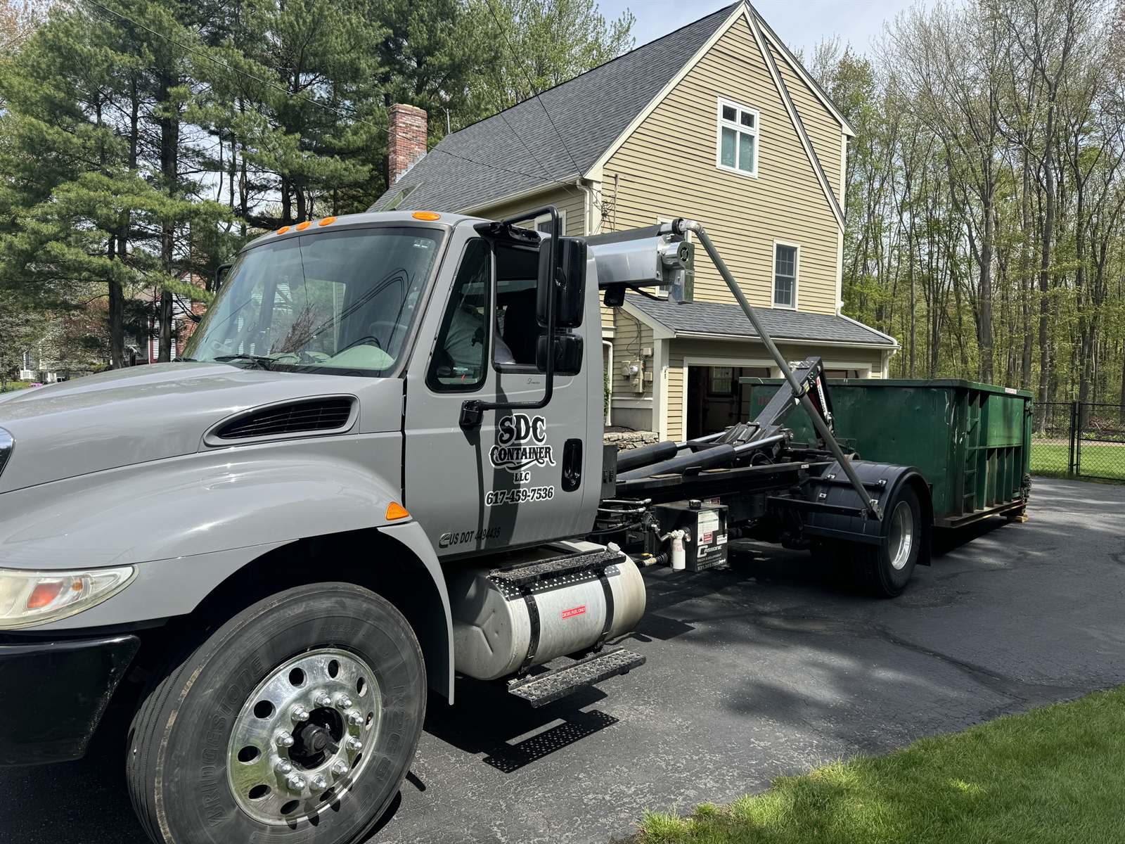 An SDC Container roll-off truck delivering a container to a residential driveway